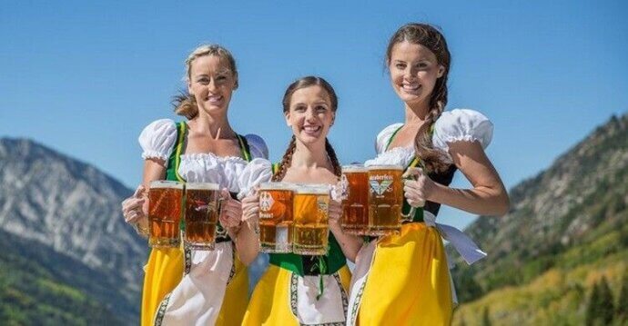 три девушки с бокалами пива на фоне гор