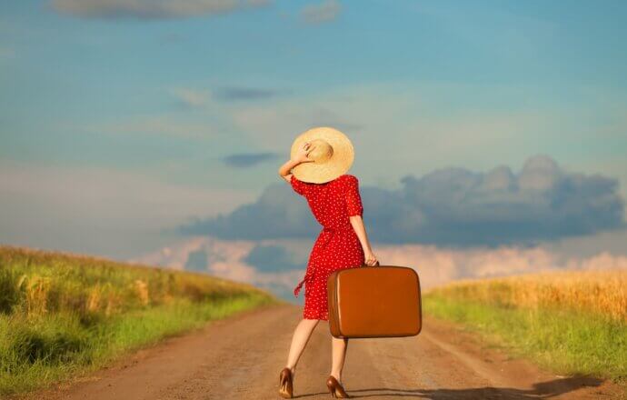 девушка в красном платье с чемоданом в руке
